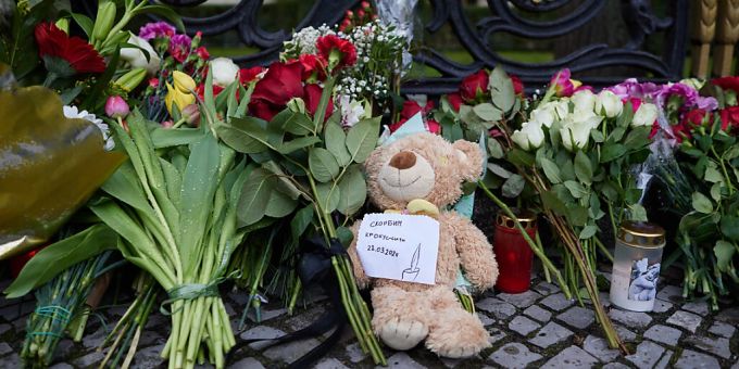 Blumen und ein Teddybär liegen am Zaun der russischen Botschaft in Berlin. Russland