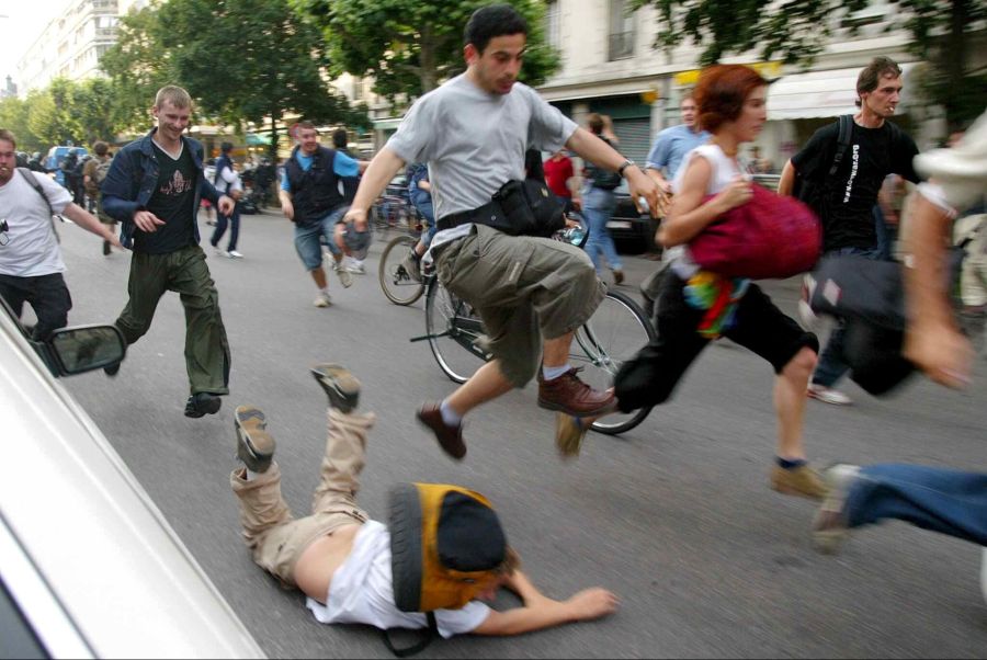 Ein junger Mann stürzt zu Boden, während Demonstranten bei Zusammenstössen mit der Polizei in Genf am Dienstag, dem 3. Juni 2003, vor Wasserwerfern und Tränengas fliehen.