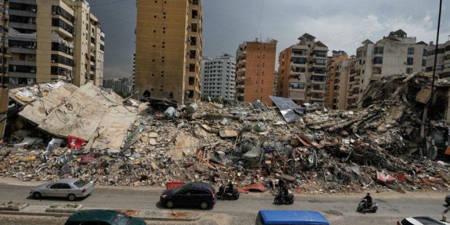 ARCHIV - Anwohner fahren an den Trümmern zerstörter Gebäude in Dahija, einem südlichen Vorort von Beirut, Libanon, vorbei. Nach wochenlangen Kämpfen zwischen Israel und der libanes...