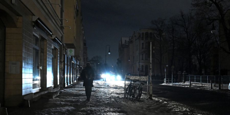 dpatopbilder - Eine Person läuft eine dunkle Straße in Zehlendorf entlang, die nur durch einen Autoscheinwerfer erhellt wird. Zehntausende Menschen im Südwesten der Hauptstadt haben ...