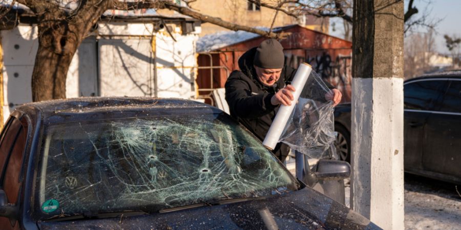 ARCHIV - Ein Autobesitzer wickelt sein Auto in Plastik ein, nachdem es nach einem russischen Raketen- und Drohnenangriff in Kiew, Ukraine, beschädigt wurde. Foto: Dan Bashakov/AP/dpa