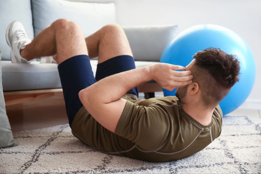Mann macht Crunches im Wohnzimmer