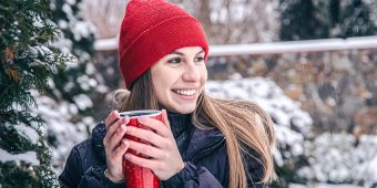 Lächelnde Frau im Winter mit Getränk