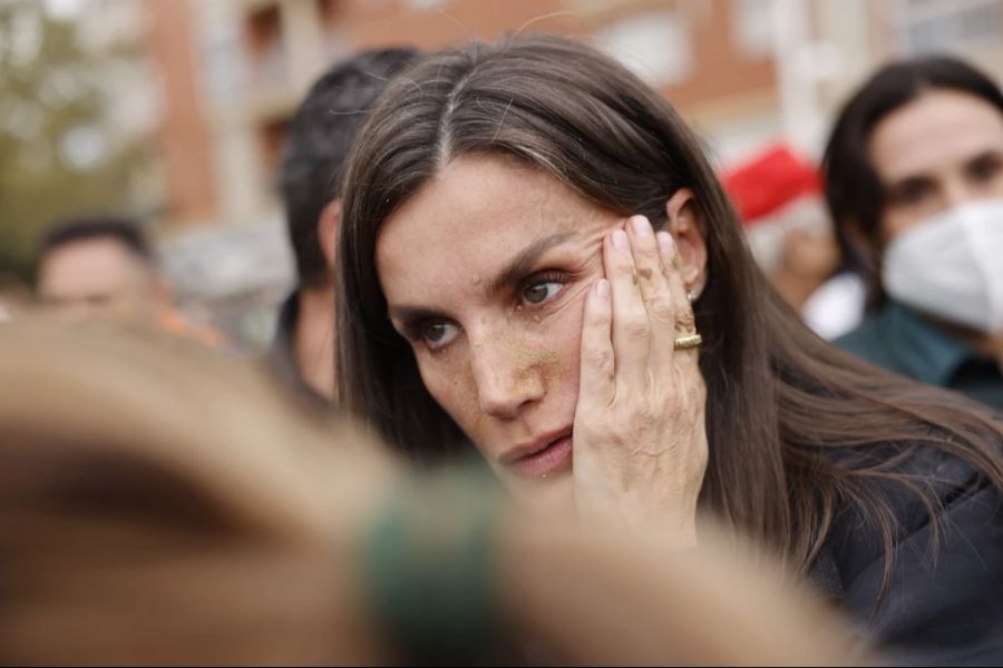 Königin Letizia wischt sich Schlamm aus dem Gesicht.