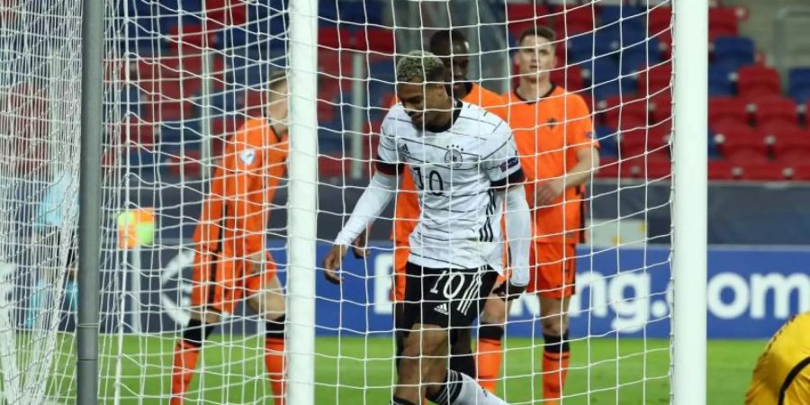 Deutschlands Lukas Nmecha (M) holt nach seinem Tor zum 1:1 den Ball aus dem Tor - der niederländische Torwart Kjell Scherpen (r) sitzt geschlagen auf dem Rasen. Foto: Csaba Domotor/dpa
