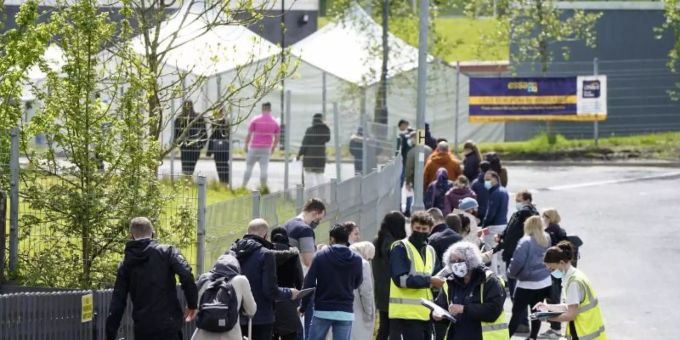 Menschen warten in einer Schlange vor dem mobilen Covid-Impfzentrum an der ESSA-Akademie in Bolton. grossbritannien