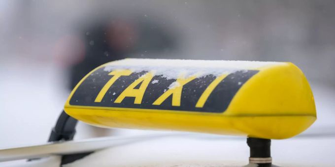 Schneeflocken fallen auf ein Taxi-Schild. (Symbolbild) Taxi