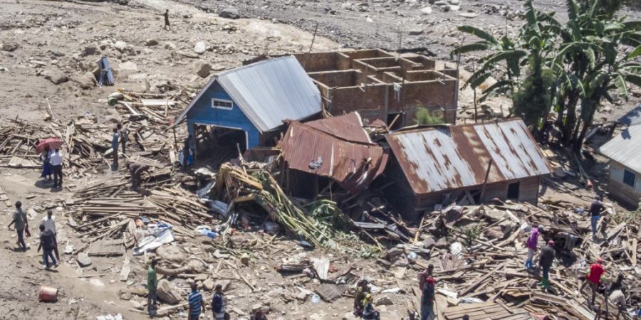 dpatopbilder - Überlebende gehen inmitten von Trümmern neben zerstörten Gebäuden nach den Überschwemmungen im Dorf Nyamukubi in der Provinz Süd-Kivu im Kongo. Es werden noch immer mehrere hundert Menschen vermisst. Foto: Justin Kabumba/AP/dpa