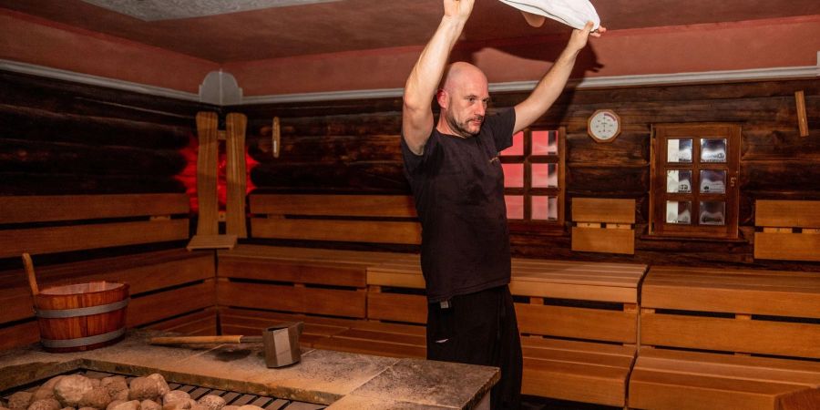 Saunameister Marcus Krämer wirbelt in einer Sauna der SchwabenQuellen Stuttgart mit einem Handtuch heisse Luft umher.