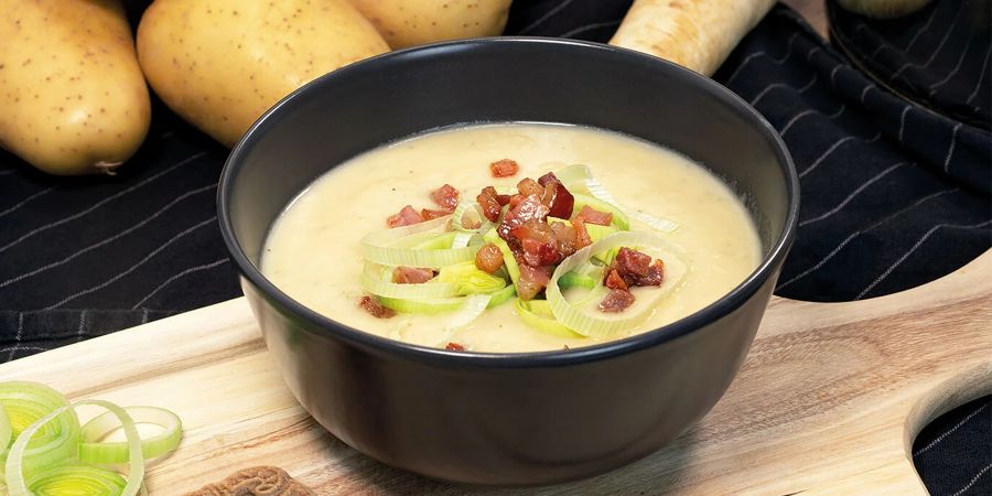 Die Kartoffelsuppe mit Spekulatiuscreme wird mit knusprigem Würfelspeck getoppt.
