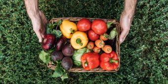 männerhände halten korb mit gemüse und obst