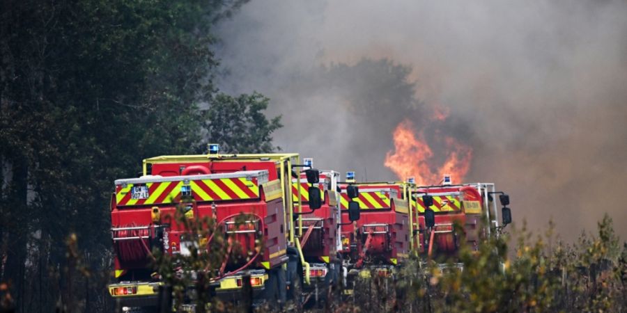 Feuerwehrleute bekämpfen ein Feuer, während in der Nähe von Le Las bei Bordeaux Waldbrände wüten. Foto: Emma Da Silva/AP/dpa