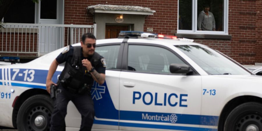 Eine Person schaut aus dem Fenster, während die Polizei zu einer Schießerei im Stadtteil Côte-des-Neiges in Montreal ausrückt. Foto: Christopher Katsarov/The Canadian Press/AP/dpa