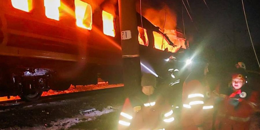 HANDOUT - Auf diesem vom ukrainischen Katastrophenschutz zur Verfügung gestellten Foto bekämpfen Feuerwehrleute das Feuer, nachdem russische Drohnen einen Personenzug in der Region Ch...