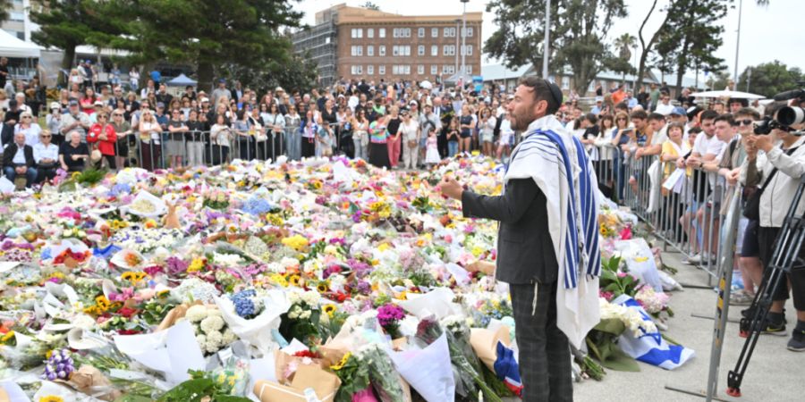Ein Rabbiner spricht zu den Trauernden an einer behelfsmäßigen Gedenkstätte am Bondi Beach in Sydney, Australien. Foto: Mick Tsikas/AAP/dpa