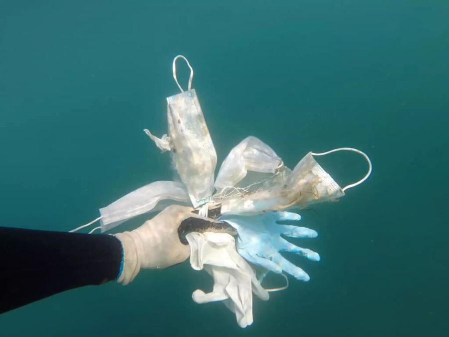 Schutzmasken und Latexhandschuhe treiben im Meer.