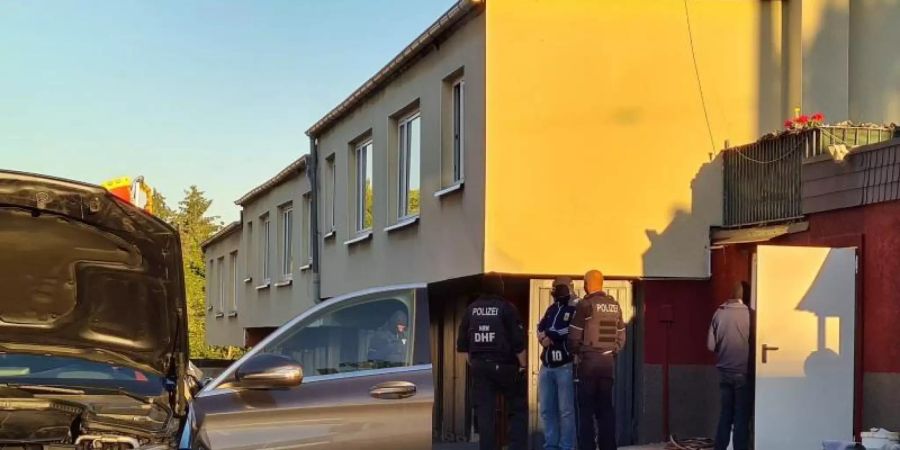 Polizeibeamte stehen auf einem Anwesen. Bei einer Razzia gegen Clankriminalität sind in Nordrhein-Westfalen am frühen Morgen mehrere Wohnungen und Firmen durchsucht worden. Foto: Gianni Gattus/dpa