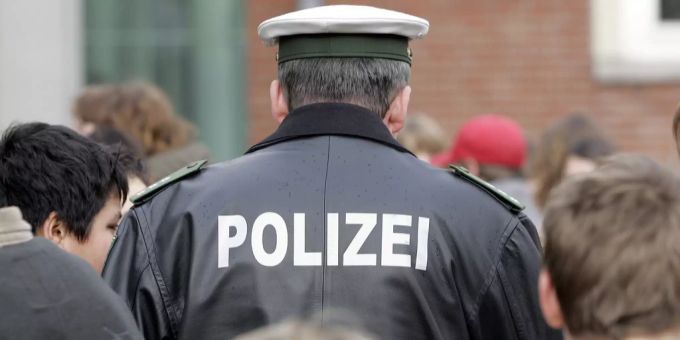 Ein Polizist in Deutschland steht inmitten von Jugendlichen. Polizist Schuhe