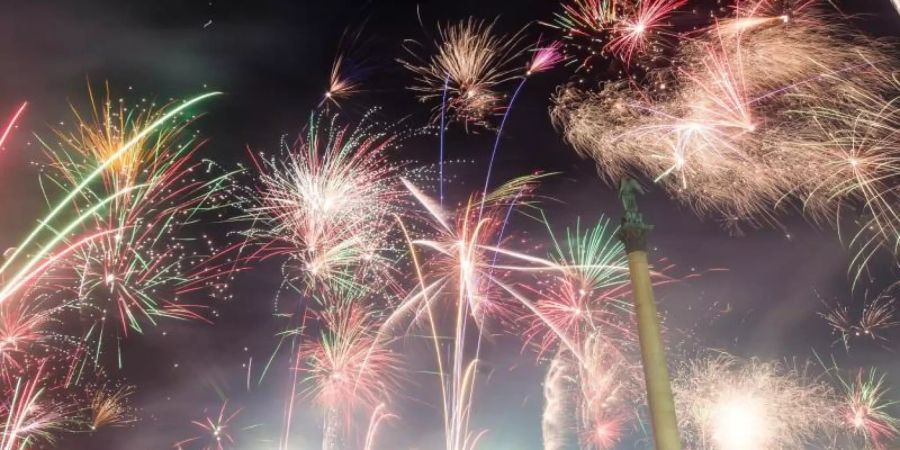 Zahlreiche Menschen feiern auf dem Schlossplatz in Stuttgart mit reichlich Feuerwerk in das neue Jahr. Foto: Christoph Schmidt/dpa