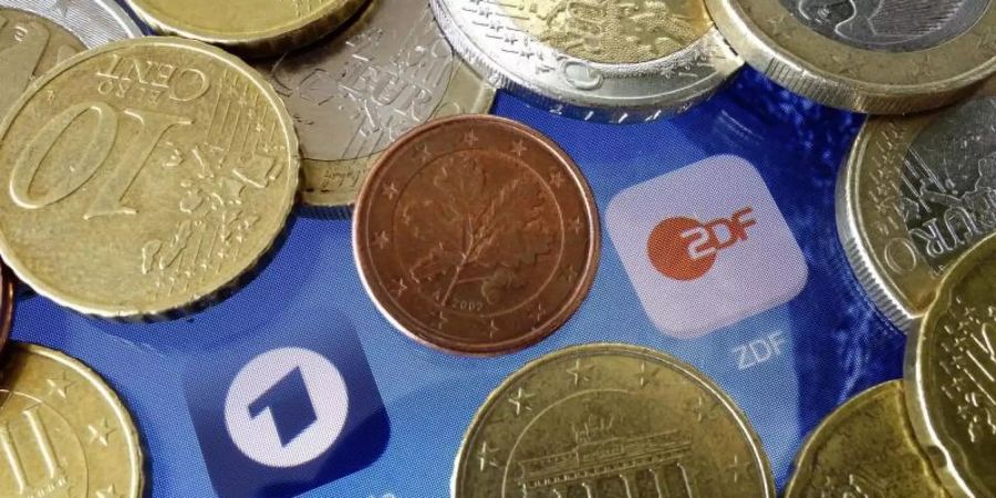 Euromünzen liegen neben den Logos der Apps von ARD und ZDF. Foto: Soeren Stache/dpa