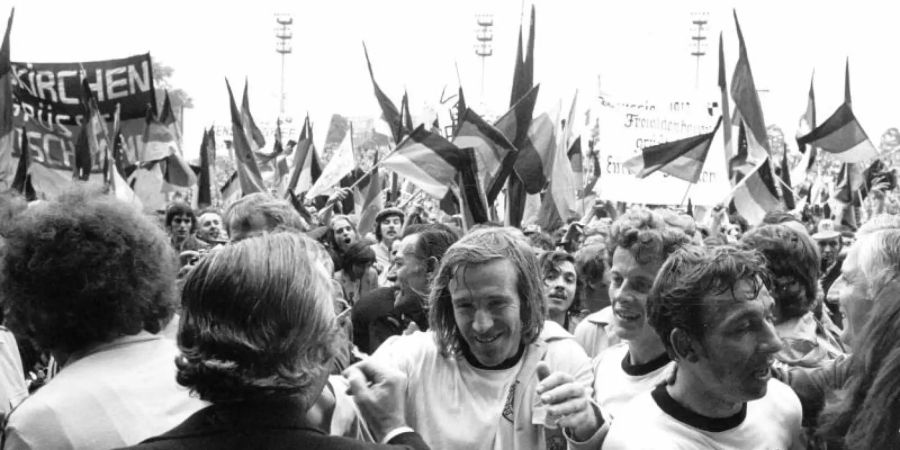 Durch jubelnde Fans bahnen sich (M-r) Günter Netzer, Herbert Wimmer und Horst-Dieter Höttges ihren Weg. Foto: Werner Baum/dpa/Archivbild