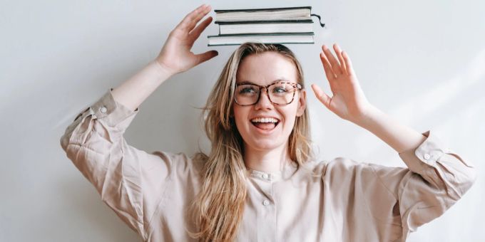 Lesen bringt einen enormen Mehrwert in Ihr Leben und Ihre persönliche Entwicklung. Frau mit Büchern auf dem Kopf