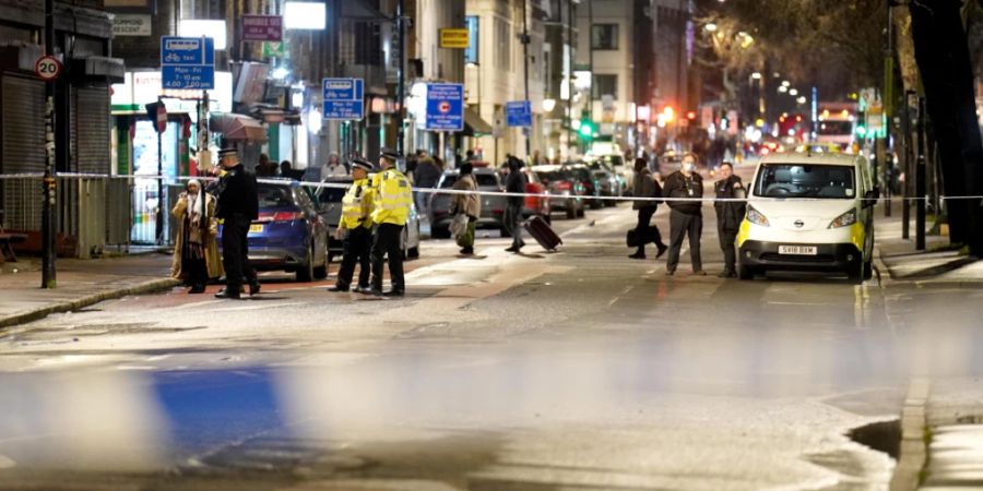 Polizisten stehen in der Nähe des Tatorts in London, nachdem Schüsse aus einem fahrenden Auto abgefeuert wurden. Foto: James Manning/PA Wire/dpa