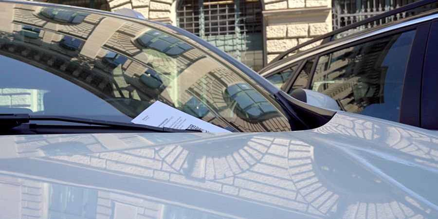 Ein Strafzettel wegen Falschparkens an der Windschutzscheibe eines Autos. (Symbolbild)