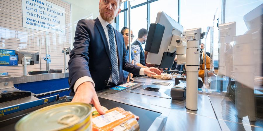 Michael Kretschmer (CDU), Ministerpräsident von Sachsen, zieht in Görlitz Lebensmittel über die Scannerkasse.