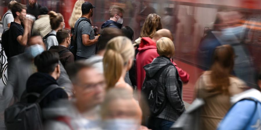 Fahrgäste warten an einem Gleis im Tiefbahnhof des Frankfurter Hauptbahnhofs, während eine S-Bahn einfährt.