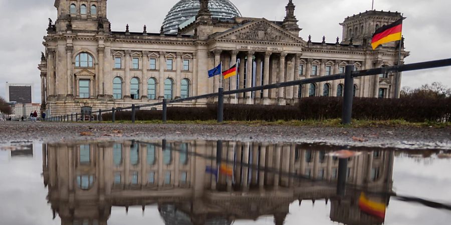 ARCHIV - Das Reichstagsgebäude spiegelt sich am Morgen in einer Pfütze. Foto: Christoph Soeder/dpa