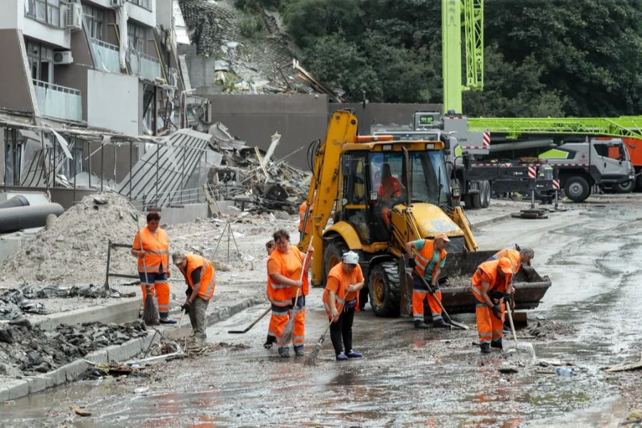 Helfer schaufeln die verwüstete Strasse in Kiew frei.