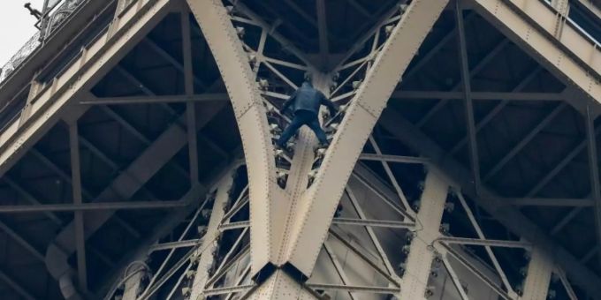 Ein Kletterer am Eiffelturm. Immer wieder besteigen vorwiegend junge Menschen hohe Gebäude ungesichert auf der ganzen Welt. Meistens für Klicks online. kletter