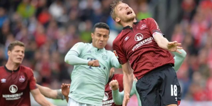 Nürnbergs Hanno Behrens (r) im Kopfballduell gegegn Bayerns Thiago. Foto: Timm Schamberger