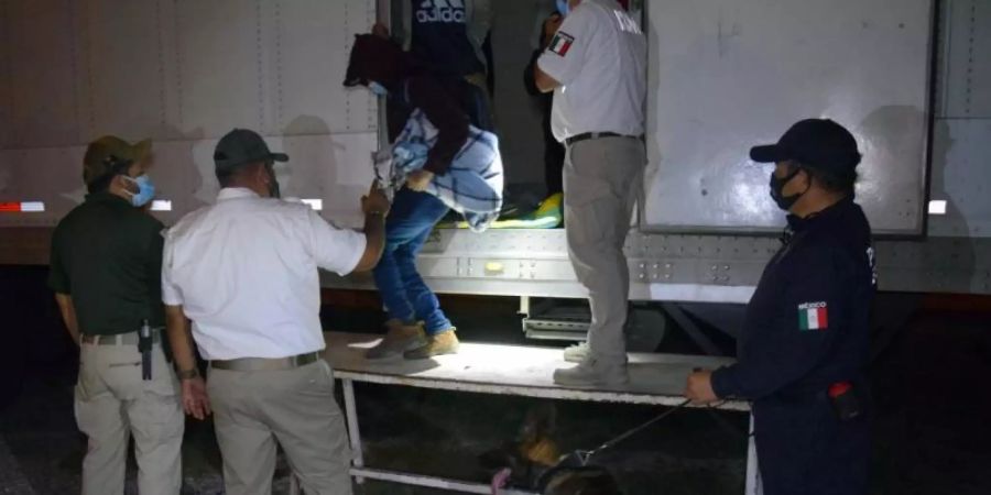 Polizisten und Offiziellle helfen Migranten aus Sattelzügen. Mexikanische Soldaten haben in den Aufliegern dreier Sattelzüge insgesamt 652 mittelamerikanische Migranten in versiegelten Kühlkammern entdeckt. Foto: --/Regierung des Bundesstaates Tamaulipas/dpa