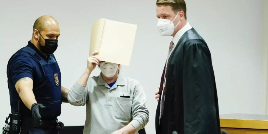 Der Angeklagte (M) mit seinem Anwalt Steffen Lindberg (r) und einem Justizbeamten zu Prozessbeginn im September im Gericht. Foto: Uwe Anspach/dpa-pool/dpa