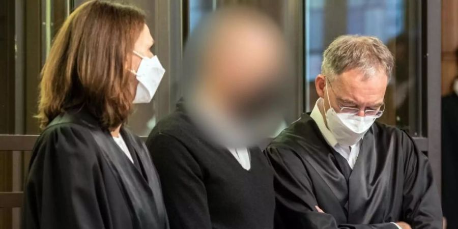 Der Angeklagte (M) zwischen seinen Anwälten in Berlin. Foto: Paul Zinken/dpa