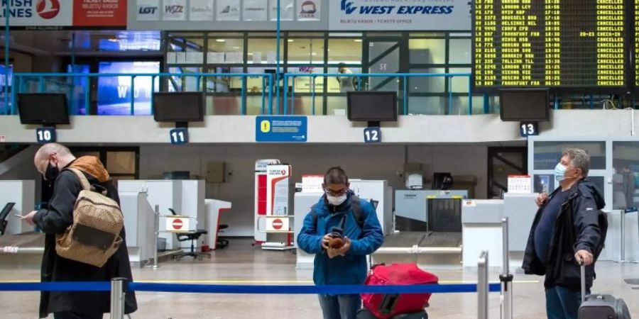 Passagiere mit Smartphones in einer Schlange im Internationalen Flughafen von Vilnius. Foto: Mindaugas Kulbis/AP/dpa