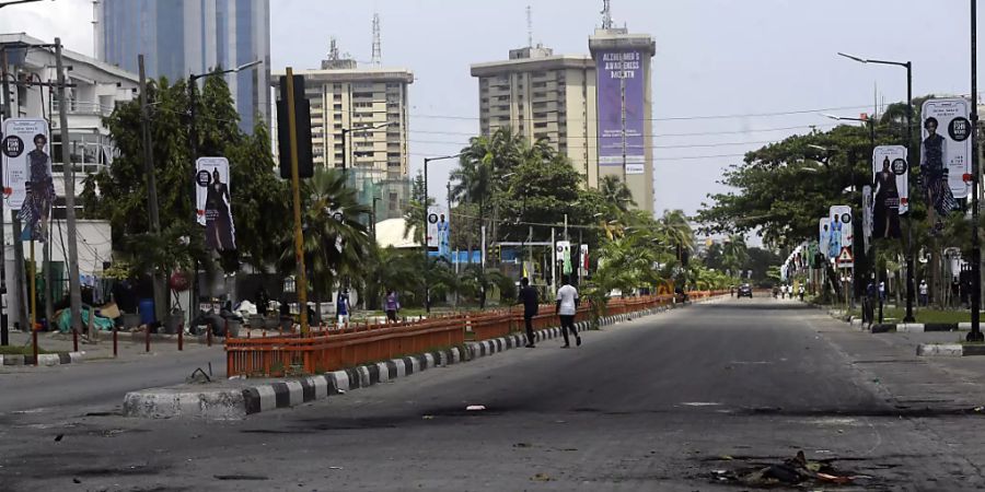 Auf einer sonst leeren Strasse liegen die Überreste von abgebrannten Strassenblockaden. Nach einem Blutbad bei einer Kundgebung gegen Polizeiübergriffe gehen die Proteste im westafrikanischen Nigeria unvermindert weiter. Foto: Sunday Alamba/AP/dpa