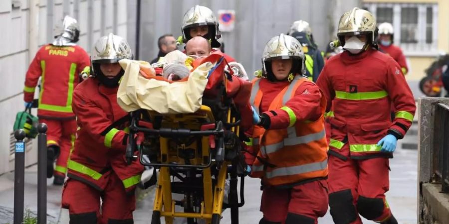 Einsatzkräfte der Feuerwehr schieben eine Trage mit einem Verletzten. Foto: Alain Jocard/AFP/dpa