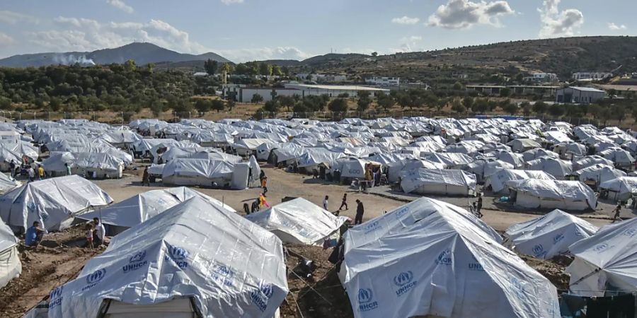 ARCHIV - Migranten gehen nach starken Regenfällen durch das Flüchtlingslager «Kara Tepe». Das provisorische Zeltlager «Kara Tepe» war in Windeseile errichtet worden, nachdem das ursprüngliche Lager Moria bei einem Grossbrand fast völlig zerstört worden war. Foto: Panagiotis Balaskas/AP/dpa