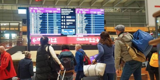 Reisende stehen am Flughafen BER vor einer Info-Tafel. Foto: Joerg Carstensen/dpa Reisende stehen am Flughafen BER vor einer Info-Tafel. Foto: Joerg Carstensen/dpa