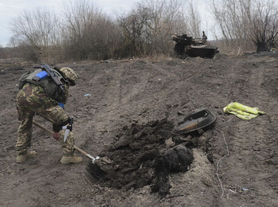 Ein Soldat der ukrainischen Armee hebt nahe Kiew ein Grab für einen getöteten russischen Soldaten aus.