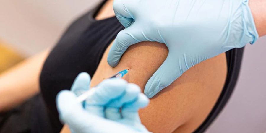 Eine Frau wird von einem Arzt gegen das Coronavirus geimpft. Foto: Moritz Frankenberg/dpa