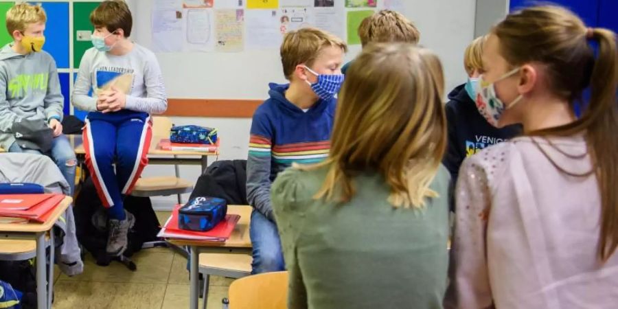 Schülerinnen und Schüler einer sechsten Klasse einer Schule in Kiel warten in ihrem Klassenzimmer auf den Unterrichtsbeginn. Foto: Gregor Fischer/dpa