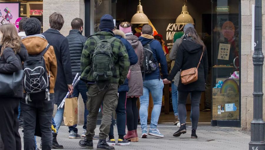 Einkäufer stehen vor einem Geschäft in Nürnberg in der Warteschlange.