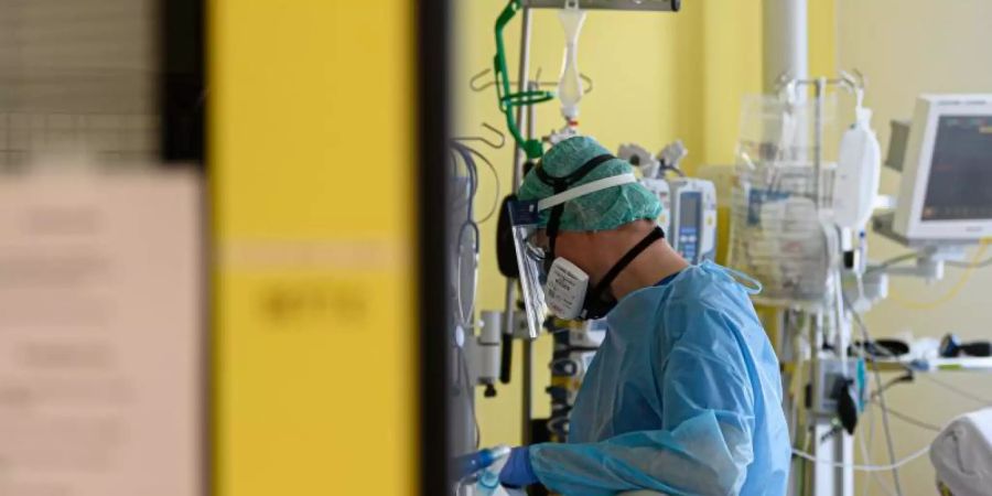 Ein Intensivpfleger versorgt auf der Covid-19 Intensivstation (ITS) im Städtischen Klinikum Dresden einen Corona-Patienten. Foto: Robert Michael/dpa-Zentralbild/dpa
