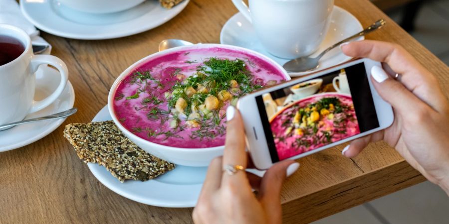 Frau macht Foto mit Handy von gesundem Essen.