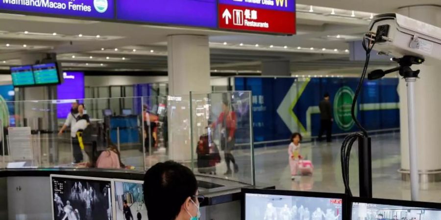 Ein Beamter der Gesundheitsüberwachung überprüft am Flughafen von Hongkong mit Wärmebildkameras die Temperatur von Reisenden. Foto: Andy Wong/AP/dpa