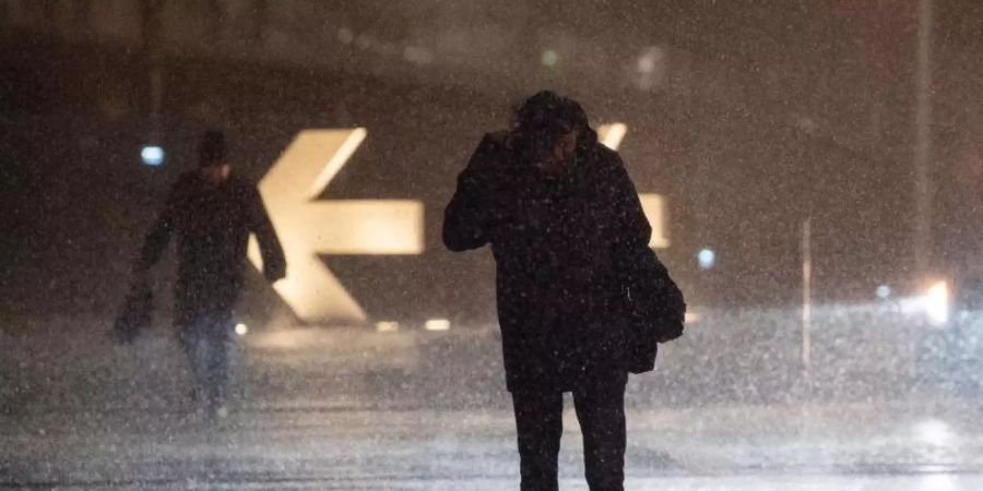Passanten kämpfen sich durch strömenden Regen. Foto: Marijan Murat/dpa